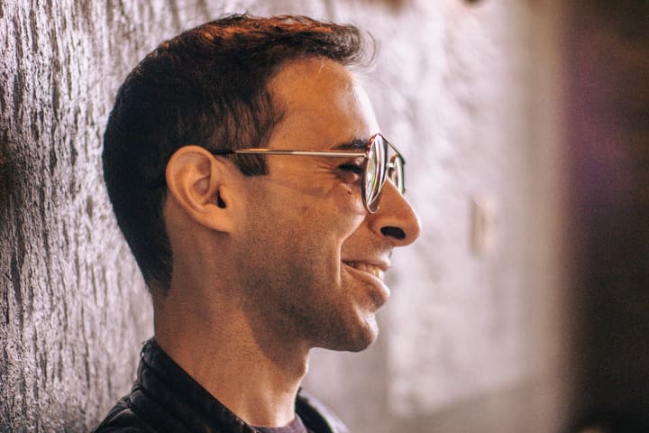 Bandmitglied im Profil, lächelnd, mit Brille