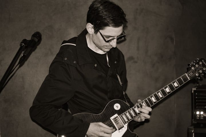 Gitarrist mit E-Gitarre neben einem Mikrofonständer, Schwarzweiß