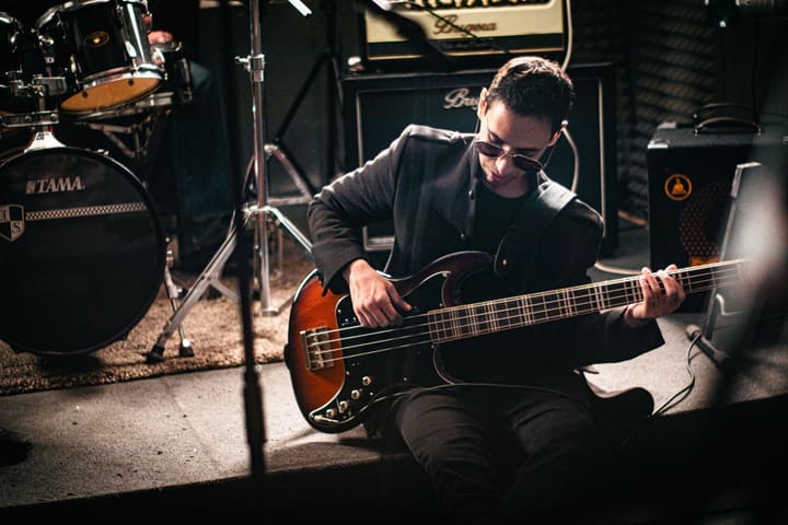 Bassist im Proberaum zwischen Schlagzeug und Verstärker