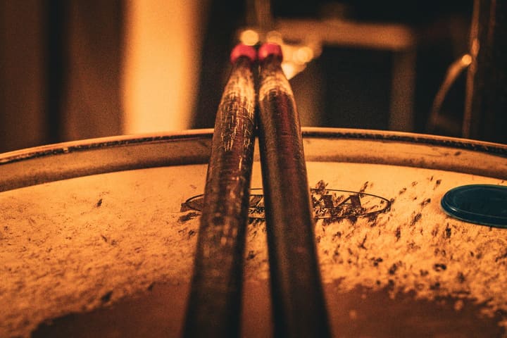 Zwei Drumsticks auf einem Schlagzeugfell, warmes Licht