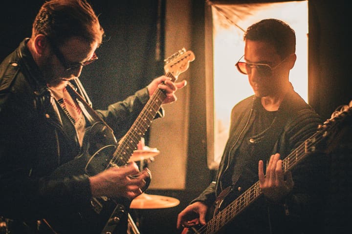 Gitarrist und Bassist im Fensterlicht des Proberaums