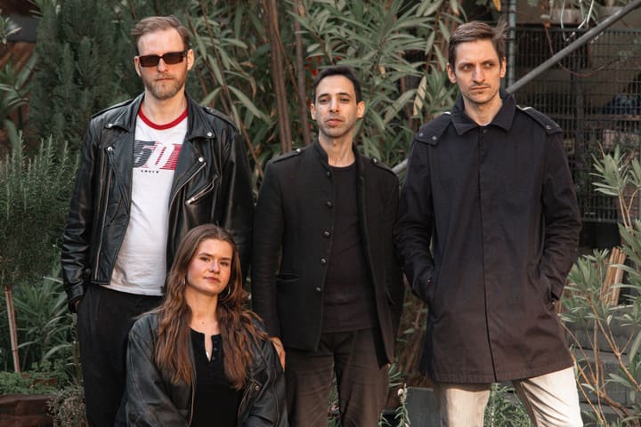 Die Band zwischen Pflanzen im Garten, die Schlagzeugerin vorn sitzend